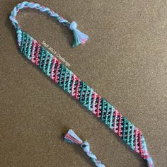 a crocheted bracelet with tassels and beads on a brown table next to a pair of scissors