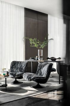 a black and white living room with two chairs, a coffee table and a vase