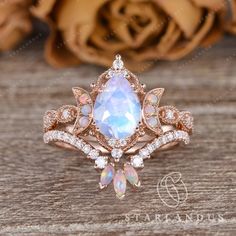 an opal and diamond ring on a wooden table with roses in the back ground