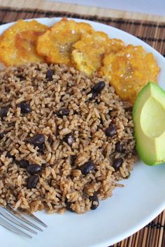 a white plate topped with rice and beans next to an avocado