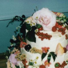 a multi layer cake decorated with flowers and fruit