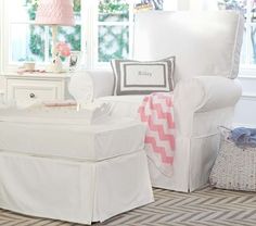 a living room with white furniture and pink accents