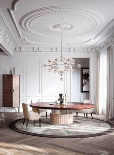 an elegant dining room with white walls and wood flooring, chandelier above the table