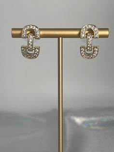 The Gold CZ Huggie Earrings are the epitome of elegance and sparkle, featuring a sleek gold finish on a snug, huggie design that's lavishly adorned with cubic zirconia stones for an irresistible glitter. These earrings are a perfect blend of sophistication and glamour, designed to hug the earlobe gently, making them an ideal accessory for both day-to-day elegance and special occasions. Length: 21.5 mm Width: 11.1 mm Closure: Bullet with Disc Backs Material: Brass with 18K Gold Plating with Rhodi Luxury Hinged Huggie Earrings, Gold Sparkling Drop Clip-on Earrings, Elegant Gold Huggie Earrings For Party, Elegant Cubic Zirconia Hoop Earrings With Bling, Gold Sparkling Crystal Hoop Earrings, Elegant Gold Hoop Earrings With Bling, Sparkling Gold Crystal Hoop Earrings, Dazzling Gold Metal Earrings, Gold Dazzling Cubic Zirconia Diamond Earrings