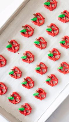 red pretzels with green leaves on them are in a white tray, ready to be eaten