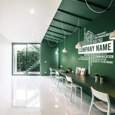 an office with green walls and white chairs in front of a long table that has writing on the wall