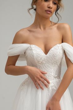 a woman in a white wedding dress with her hands on her hips, posing for the camera