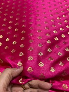 a person is holding onto a pink and gold cloth