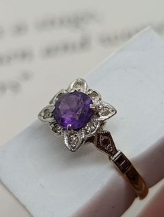 Vintage Charm Meets Art Deco Elegance: Amethyst & Diamond Daisy Cluster Ring (UK O ½) Calling all jewellery lovers! This exquisite ring is a must-have for your collection. ✨ Imagine the sparkle of a deep violet amethyst, surrounded by delicate diamond petals. ✨ The intricate details of the millegraine etching adding a touch of vintage magic. ✨ The luxurious feel of 18ct gold and platinum against your skin. This stunning ring offers all this and more! Here's what makes it special: Beautiful 0.6ct Formal Purple Brilliant Cut Gemstones, Purple Brilliant Cut Diamond Ring For Formal Occasions, Formal Purple Diamond Ring With Brilliant Cut, Yellow Gold Amethyst Ring With Brilliant Cut, Brilliant Cut Yellow Gold Amethyst Ring, Purple Sapphire Ring With Brilliant Cut, Art Deco Round Sapphire Gemstone Ring, Brilliant Cut Amethyst Gemstones For Formal Occasions, Formal Purple Sapphire Ring With Diamond