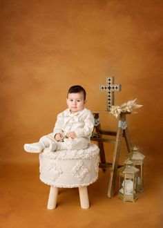 a young boy sitting on top of a stool next to a cross and lantern in the background