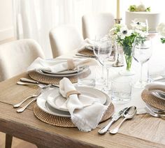 the table is set with silverware and white flowers