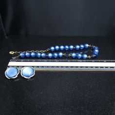 *Description: This is a great Moonglow set by Lisner from the 1950s. The medium blue moonglow Lucite beads also have Lucite clear blue faceted beads with filigree bead caps as in three sections. There are twenty-two Lucite Moonglow beads and three inches of extension chain. The Lisner tag is on one end with the hook clasp with the name Lisner on the back at the other end. The matching blue Moonglow clip on earrings are a little over an inch with the Moonglow cabochon framed in a gold tone frame. Retro Beaded Evening Jewelry, Retro Beaded Jewelry For Evening, Vintage Blue Necklace For Evening, Blue Beaded Evening Jewelry, Blue Beaded Jewelry For Evening, Blue Beaded Retro Jewelry, Retro Blue Beaded Jewelry, Retro Blue Jewelry For Party, Vintage Blue Jewelry For Evening