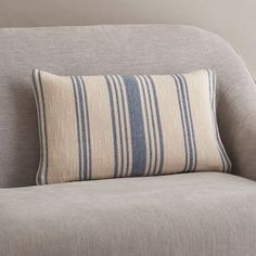 a gray couch with a blue and white striped pillow on it's backrest