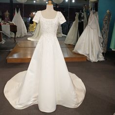 a white wedding dress on display in a bridal room with mannequins