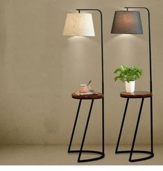 two floor lamps with plants on them next to each other