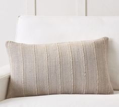 a white couch with a striped pillow on it's back and armrests