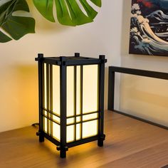 a lamp that is on top of a wooden table next to a potted plant