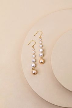 From elegant evenings to soiree sweetness, the Lulus Ideal Composure White Pearl Drop Earrings can do it all! Shiny, gold-toned metal provides a subtle backdrop for a string of luminous pearls of increasing sizes that fall in a drop-style silhouette. The last pearl on each strand has a subtle rosy hue, for an extra chic finish. Fishhook backs. Earring Measure 2" Long. Imitation Gold Plated. 5% Brass, 95% Plastic Pearl. Imported. Lulus | Ideal Composure White Pearl Drop Earrings. Jewelry Photography, Pearl Drop Earrings, Pearl Drop, White Pearl, Gold Tone Metal, Gold Wedding, Pearl White, Faux Pearl, Bridal Jewelry