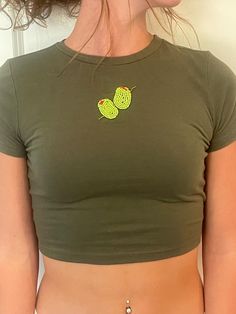 a woman wearing a green crop top with an embroidered butterfly on it