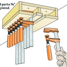 a hand is holding an orange and white tool in front of a rack with eight screws