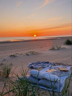 the sun is setting on the beach with blankets