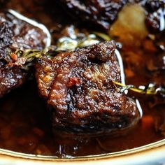 two pieces of cooked meat sitting on top of a brown sauce in a white bowl