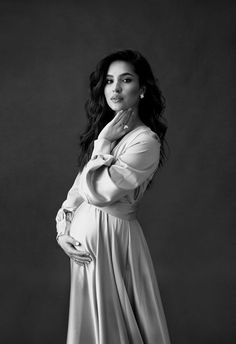 a black and white photo of a woman in a long dress posing for the camera