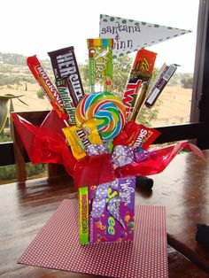 a vase filled with candy and lollipops on top of a wooden table