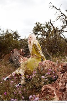 a woman sitting on top of a pile of rocks in the middle of a field