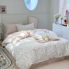 a white bed sitting in a bedroom next to a window with curtains on the windowsill