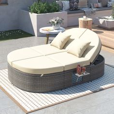 an outdoor daybed with pillows on it in the middle of a patio area next to a table and chairs