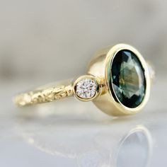 a close up of a ring with a green stone on it's side and a diamond in the middle