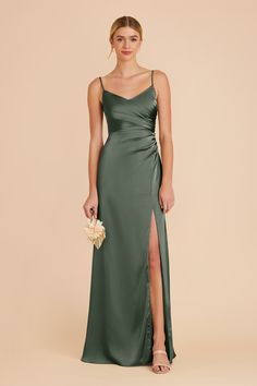 a woman in a long green dress with a slit down the side and her hand on her hip