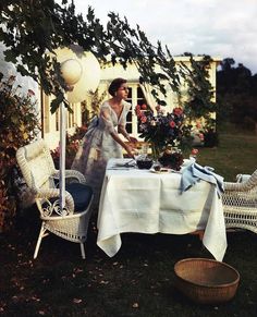 a woman standing in front of a table with flowers on it and an umbrella over the table