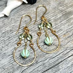 These Vintage style earrings feature a mint green melon bead falling from gold-filled chain with fire polished soft green accent beads and a cold-forged gold hoop all falling from handmade jeweler's brass ear wires.  * Earrings Measure: 2 3/8" long x 7/8" wide * Czech Glass Beads * Jeweler's Brass Handmade Ear Wires & Hoops. * US Quarter Shown for Size Reference. * Item is finished and ready to ship! * Ships within 1-3 business days via USPS Ground Advantage with Tracking. * Items ship from Alaska, so please allow a little extra time for arrival! For more about these earrings and more, follow me on instagram and facebook: @907northdesigns Green And Gold Earrings, Green Melon, Earrings Diy Handmade, Vintage Style Earrings, Fancy Earrings, Focal Beads, Earrings Inspiration, Homemade Jewelry