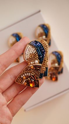 a person holding some kind of brooch in their hand and it looks like they are wearing jewelry