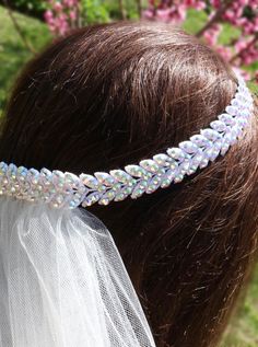 a close up of a woman wearing a wedding headband with flowers in the background