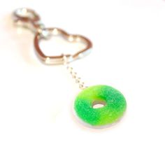 a green and white donut shaped keychain hanging from a silver chain on a white surface