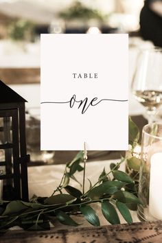 a place card sitting on top of a table next to a candle and some flowers