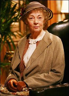 an older woman sitting in a chair wearing a hat