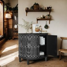 a black cabinet sitting on top of a hard wood floor next to a wooden chair