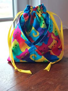 a colorful bag sitting on top of a wooden table next to a window with yellow ribbon