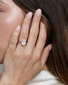 a close up of a person wearing a ring and holding their hand to her face