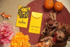 the lion king doll is next to two oranges and some other items on a table