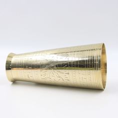 a gold cup with writing on it sitting on top of a white table next to a wall