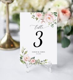 the table numbers are placed on top of each other, with pink flowers and greenery