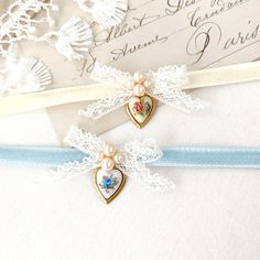 Rosy Posy Designs unique choker necklaces are handmade with soft double sided velvet ribbon. They feature delicate antique lace ribbon bows, pearl beads and rare vintage Limoge heart charms in brass frames with sweet floral designs. See photos showing two options to choose from in the drop down menu ~ blue velvet with blue rose heart charm or ivory white velvet with multicolor floral design. * Size ~ Adjustable length 12 - 15 inches with extender chain    Please check your neck size carefully as Vintage Ribbon Choker As A Gift, Vintage Ribbon Choker As Gift, Vintage Choker As Valentine's Day Gift, Vintage Ribbon Necklace For Gift, Vintage Choker For Valentine's Day, Adjustable Wedding Choker For Valentine's Day, Ribbon Choker Necklace For Weddings, Dainty Jewelry With Ribbon For Wedding, Handmade Victorian Choker For Wedding