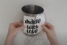 a person holding up a cup with the words made with love on it, in front of a white background