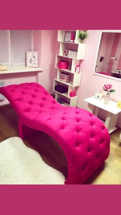 a room with a pink bed and white rugs on the wooden floor, shelving unit in the background