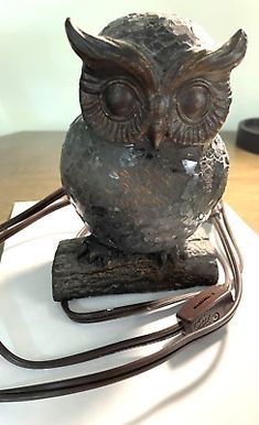 an owl statue sitting on top of a table next to a charger and cord